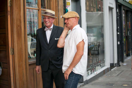 LONDON, ENGLAND - August 22, 2017 Two elderly people, dressed in the sixties style, are standing at the open door to Bricklane.のeditorial素材