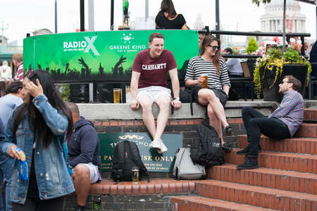 LONDON, ENGLAND - August 11 2017 A motley crowd sits outside the pub, drinks beer, talks with friends. Southbankのeditorial素材