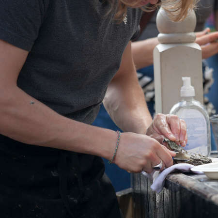 LONDON, ENGLAND - August 20, 2017 a fragment of hands that cuts oysters. Broadway road market works on Saturdaysのeditorial素材