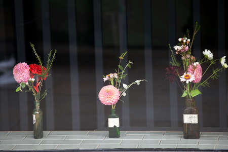 a Different kinds of bouquets of dahlias and eucalyptus leaves in vintage bottles as a shop window decorationの写真素材