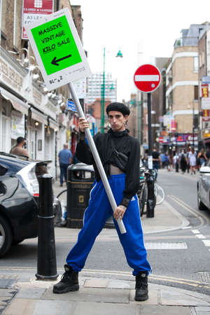 LONDON, ENGLAND - August 20, 2017 male promoter with an advertising poster stands in the middle of...