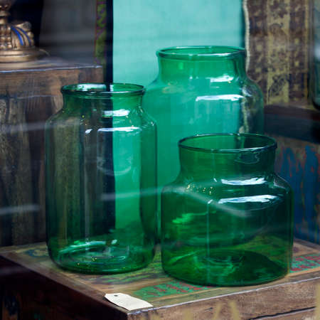 Large glass green cans that can be used as vases are displayed in the shop windowの写真素材
