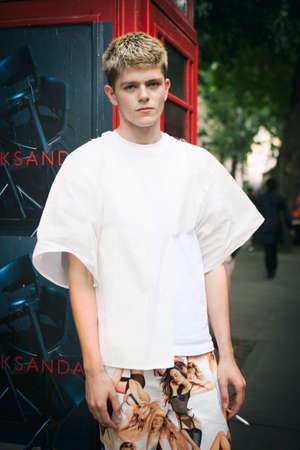 LONDON, ENGLAND - September 15, 2017 Beautiful and stylish young man in white T-shirt and colored brown training pants in front of red telephone booth. posing during the London Fashion Week. outside Eudon Choiのeditorial素材
