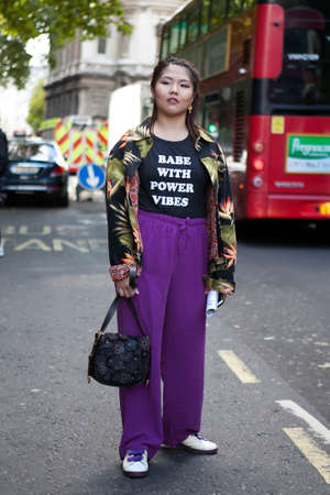 LONDON, ENGLAND - September 15, 2017 girl in a black T-shirt with the inscription "babe with power vibe" and purple trousers posing during the London Fashion Week. outside Eudon Choiのeditorial素材