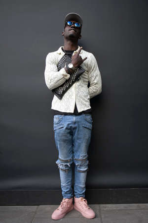 LONDON, ENGLAND - September 15, 2017 A man in a cap, in a white lace shirt, ripped jeans and pink sneakers posing during the London Fashion Week. outside Eudon Choiのeditorial素材