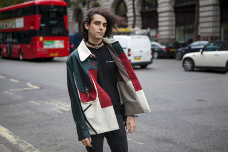 LONDON, ENGLAND - September 15, 2017 Beautiful and stylish Curly Man in a black-red-white coat posing during the London Fashion Week. outside Eudon Choiのeditorial素材