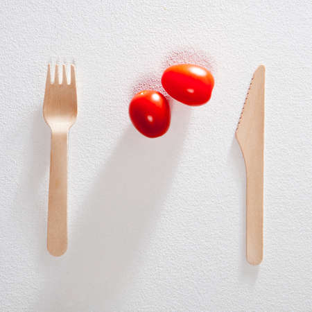 Fork with knife two cherry tomato on white background.の写真素材