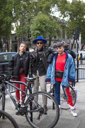 LONDON, ENGLAND - September 15, 2017 Beautiful and stylish woman in red shirt and man in blue hat posing during the London Fashion Week.のeditorial素材