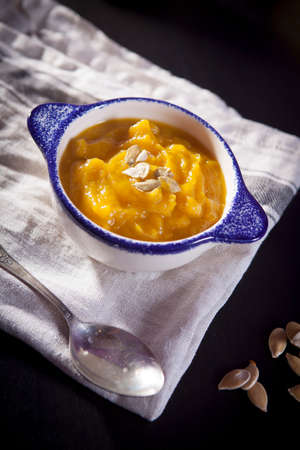 Pumpkin soup with seeds on a dark wood background. selective focus on seeds in the soupの写真素材