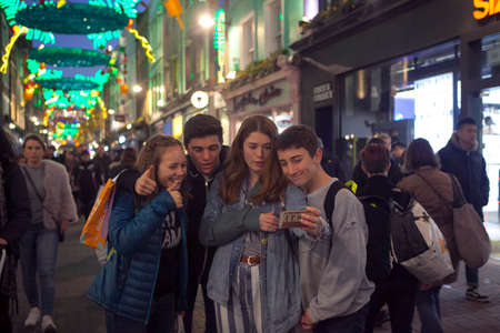 LONDON - DECEMBER 18, 2017: Teenagers make selfies. Christmas lights on Carnaby Street, London UK. Carnaby Christmas lights feature some of the most unusual decorations and lights in London.のeditorial素材