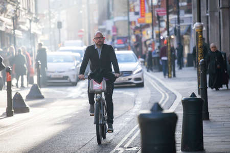 London, UK - December 22, 2017: Street Brick lane at noon in the backlight. People hurry about their business. A man riding a bicycle on the road. East Londonのeditorial素材