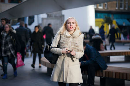 London, UK - December 22, 2017: Area near Liverpool street at noon in the backlight. People hurry about their business. East London. Blonde in a white coat walking down the streetのeditorial素材