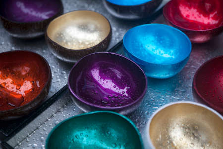 the Multicolored bowls of coconut shell with rain dropsの写真素材