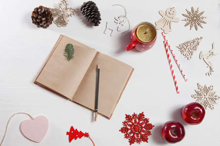 Hands of a woman who is going to draw by pencil in notebook. On the table there is a cup of tea with...