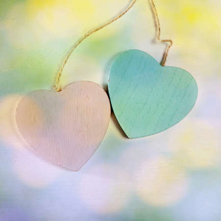 the two wooden hearts hang on a white wooden wallの写真素材