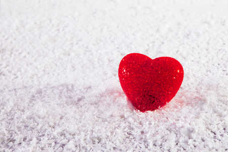 Red glass heart on white artificial snowの写真素材