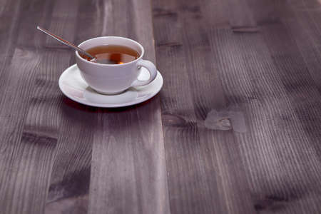 White cup of tea and saucer on a brown wooden table. Copy spaceの写真素材