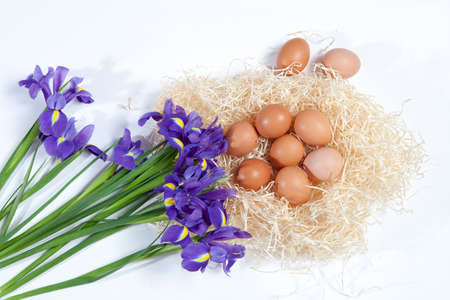 Holiday greeting card for Valentine's Day, Woman's Day, Mother's Day, Easter! Wild, purple irises and a basket with easter eggs on wooden table in the outdoors close-up.の写真素材
