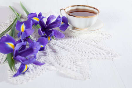 Violet Irises xiphium (Bulbous iris, sibirica) with cup of tea on white background with space for text. Top view, flat . Holiday greeting card for Valentine's Day, Woman's Day, Mother's Day, Easter!の写真素材