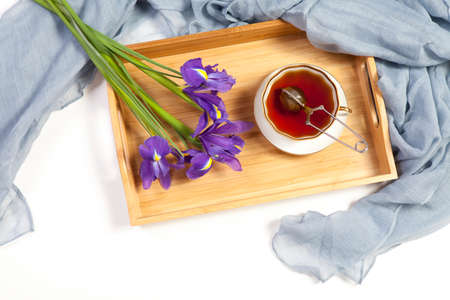 Violet Irises xiphium (Bulbous iris, sibirica) with cup of tea on white background with space for text. Top view, flat . Holiday greeting card for Valentine's Day, Woman's Day, Mother's Day, Easterの写真素材