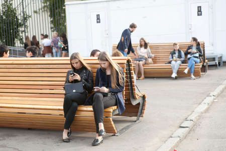 Moscow, Russia - 21 June 2017 Girls with long hair sit on a park bench and look at the phoneのeditorial素材