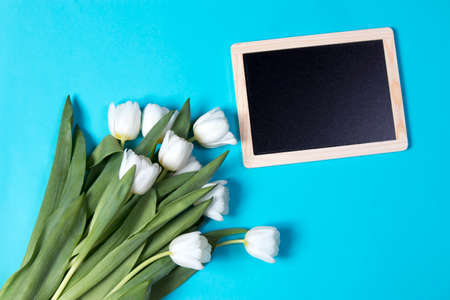 the bouquet of white tulips with black board on the blue backgroundの写真素材