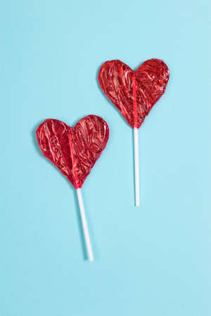 red Lollipop candy in heart shape on dark blue background.
