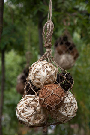 Decoration of garden.White and brown balls of vines hanging in the grid under the treeの写真素材
