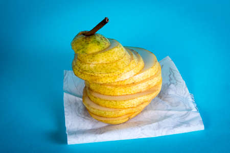 Pear, cut into thin slices, on a blue background. Conceptual postcard.の写真素材