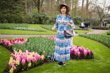 Lisse, Netherlands - April 20, 2018: Woman in traditional holland dress poses in the botanical garden of Keukenhof in springのeditorial素材