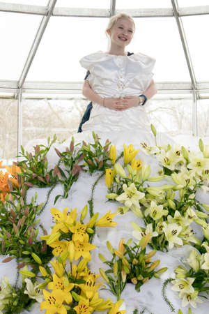 Lisse, Netherlands - April 20, 2018: A girl posing in a fake dress of lilies in a greenhouse of a botanical garden Keukenhof.のeditorial素材
