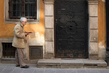 WARSAW, POLAND - APRIL 28, 2018: Old man near Late-Renaissance style burgher houses which were rebuilt after the Second World War and now form the UNESCO World Heritage Site Old Townのeditorial素材