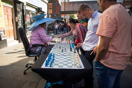 London, UK - July 22, 2018: Man playing chess with passers by in Brick Lane, London. The street is the heart of the London's Bangladeshi-Sylheti community and is famous for its many curry houses.のeditorial素材