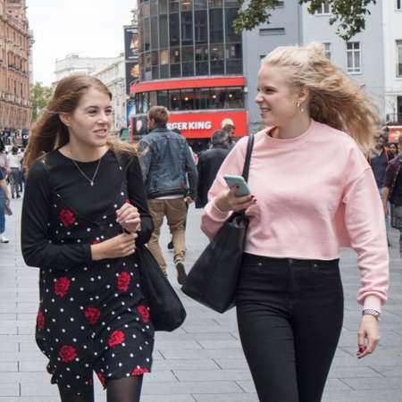 LONDON, ENGLAND - August 11 2018 Two fashionable girls talking while walkingのeditorial素材