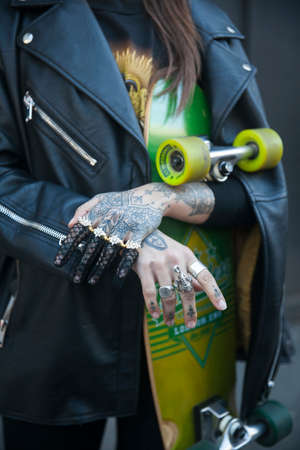 LONDON - FEBRUARY 15, 2019: Stylish attendees gathering outside 180 Strand for London Fashion Week. Girl with tattoo on her face and hands with skateboard in her hands and black leather jacketのeditorial素材