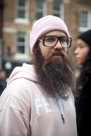 LONDON - FEBRUARY 15, 2019: Stylish attendees gathering outside 180 The Strand for London Fashion Week. the man in glasses and hat wears a pink sweatshirt with inscription "feminist"のeditorial素材