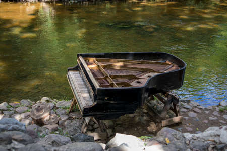 Vilnius, Lithuania - August 2018: abandoned gran piano, rundown piano by a river bank (Vilnia river) in Uzupis artists quarter in Vilnius, Lithuania, bohemian atmosphere. Republic of Uzupisのeditorial素材