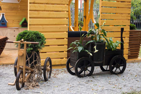 Flower stand in the form of a bicycle and a car on a wooden podium in the garden. Landscape Designの写真素材