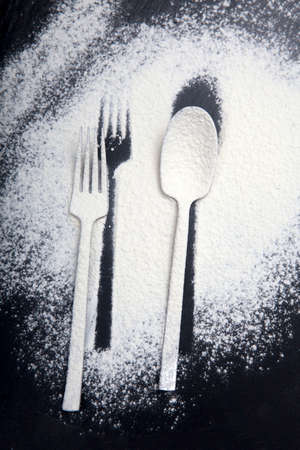 Spoon and fork silhouette made with flour on dark texture backgroundの写真素材