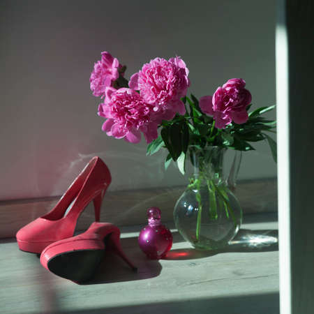 Bouquet of pink peonies is in a glass transparent vase on the floorの写真素材