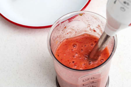 Making strawberry, banana and apricot smoothies for breakfast.