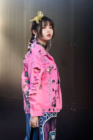 LONDON, ENGLAND - September 15, 2019 Stylish attendees gathering outside 180 Strand for London Fashion Week. Chinese girl dressed in decora japanese street style in a pink denim jacket with toy dinosaur instead of a hairpin on her headのeditorial素材