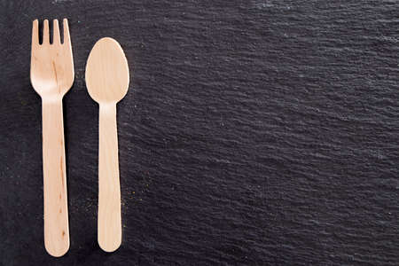 Spoon and folks on the black stone board ready to cook and taste with the ingredients of your choice.の写真素材