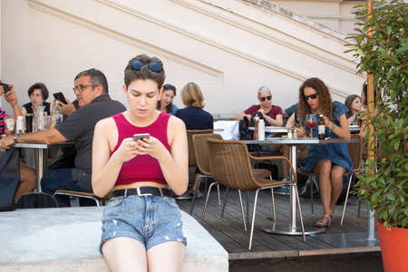 VIENNA, AUSTRIA - September 05 2019: crowded autumn streets in the city center. People eat in a street cafe. The girl is looking in mobile phoneのeditorial素材