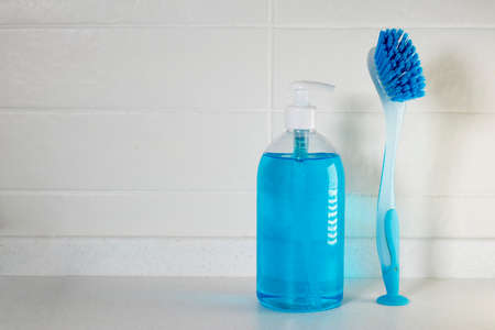 Copy space. Liquid blue soap with dispenser in a plastic bottle and a brush for cleaning ceramics