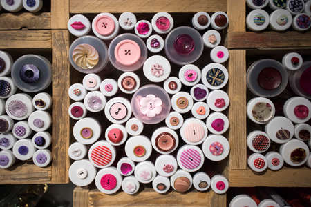 Multi-colored buttons in wooden boxes for sale in a store.の写真素材