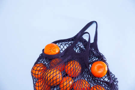 Blue string bag with tangerines on a blue paper backgroundの写真素材