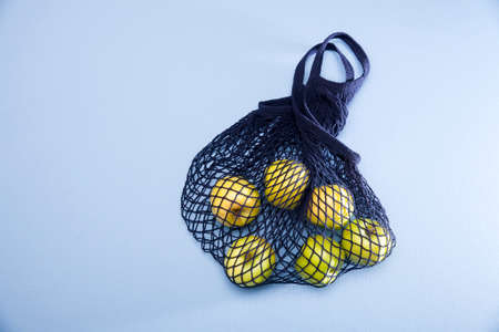 Blue string bag with green apple on a blue paper backgroundの写真素材