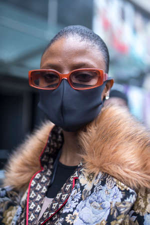 LONDON, UK- febryary 15 2020: Fashionable people on the street . Street style. Girl in a brown suit and medical mask, defends herself from a coronovirusのeditorial素材