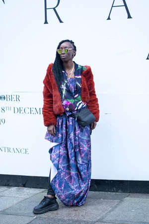 LONDON, UK- febryary 15 2020: Fashionable people on the street . Street style. Girl in a red fur coat and blue dress in sunglasses posingのeditorial素材